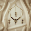 Gold necklace with purple stones and matching earrings on a beige fabric background
